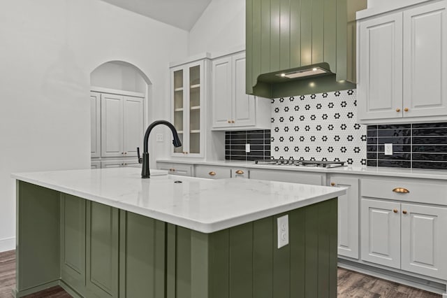 kitchen with white cabinetry, light stone countertops, a kitchen island with sink, and stainless steel gas cooktop