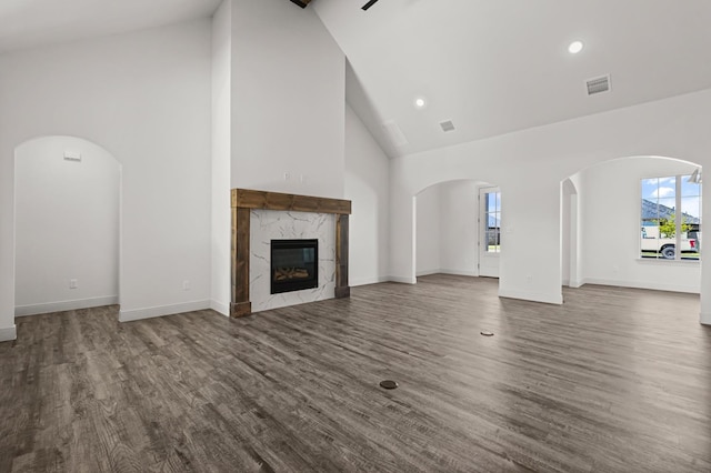 unfurnished living room featuring dark wood-type flooring, a fireplace, and high vaulted ceiling