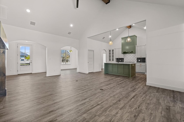 unfurnished living room featuring beam ceiling, dark wood-type flooring, and high vaulted ceiling