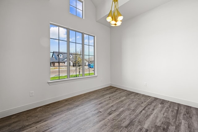 spare room with hardwood / wood-style flooring and a chandelier