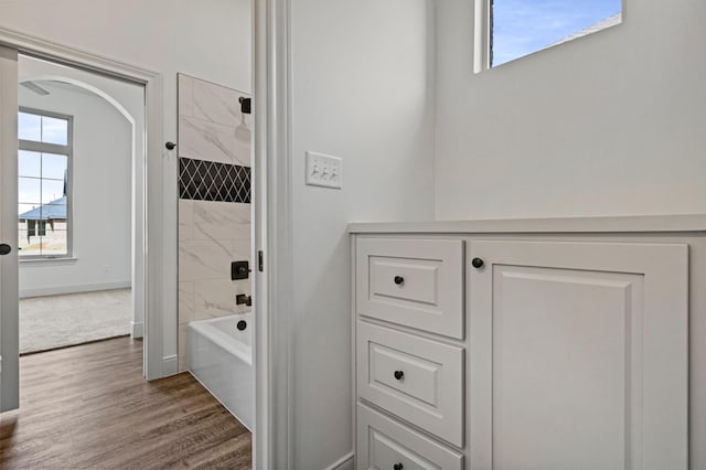 bathroom with tiled shower / bath and hardwood / wood-style floors