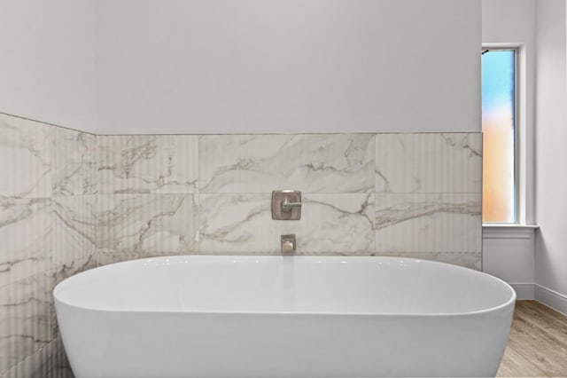 bathroom featuring a washtub, wood-type flooring, and tile walls