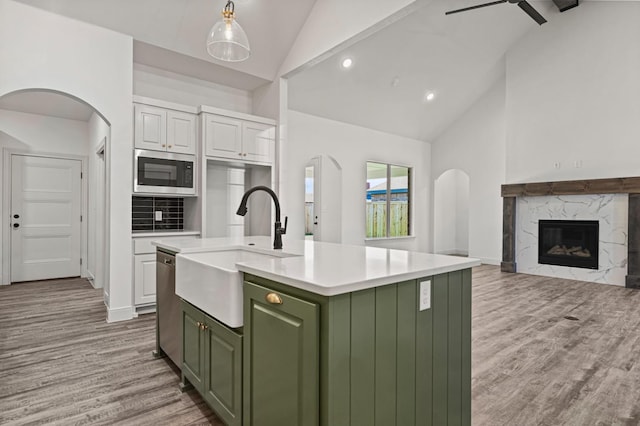 kitchen with sink, white cabinetry, appliances with stainless steel finishes, green cabinets, and a kitchen island with sink