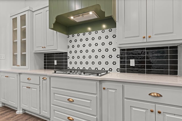 kitchen featuring stainless steel gas stovetop, white cabinetry, light stone countertops, and wall chimney exhaust hood