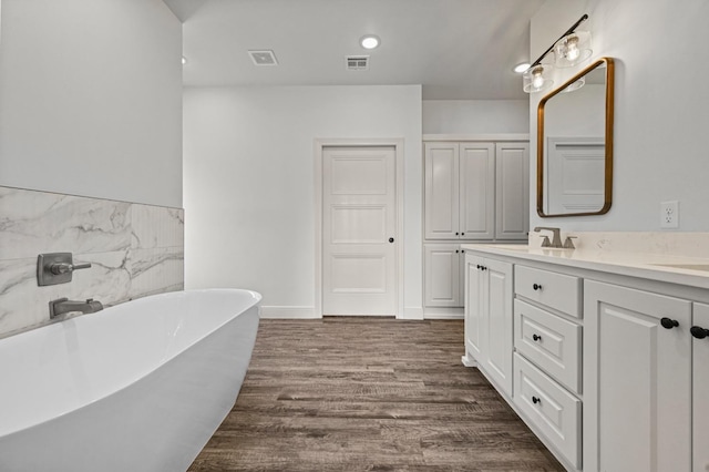 bathroom with vanity, hardwood / wood-style floors, and a tub to relax in