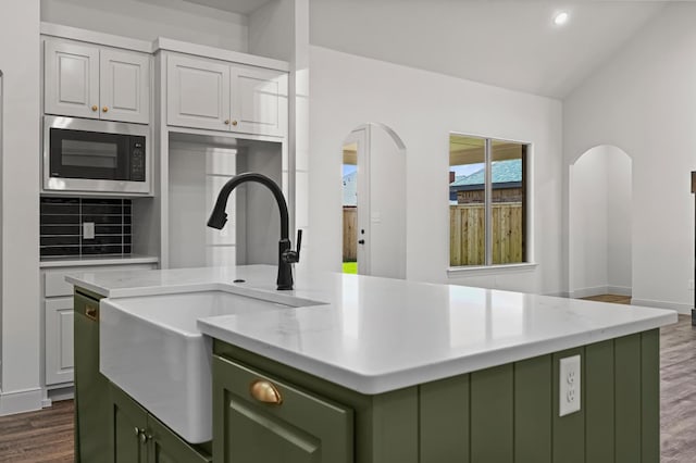 kitchen with stainless steel microwave, green cabinets, a kitchen island, and white cabinets