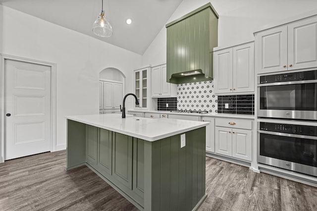 kitchen featuring pendant lighting, white cabinetry, a center island with sink, hardwood / wood-style flooring, and stainless steel appliances