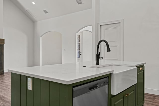 kitchen featuring sink, a kitchen island with sink, light stone counters, dark hardwood / wood-style flooring, and stainless steel dishwasher