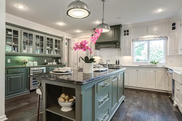 kitchen featuring white cabinetry, beverage cooler, dark hardwood / wood-style flooring, hanging light fixtures, and a center island with sink