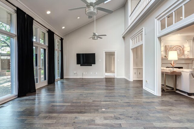 unfurnished living room with dark wood-type flooring, ceiling fan, crown molding, and high vaulted ceiling