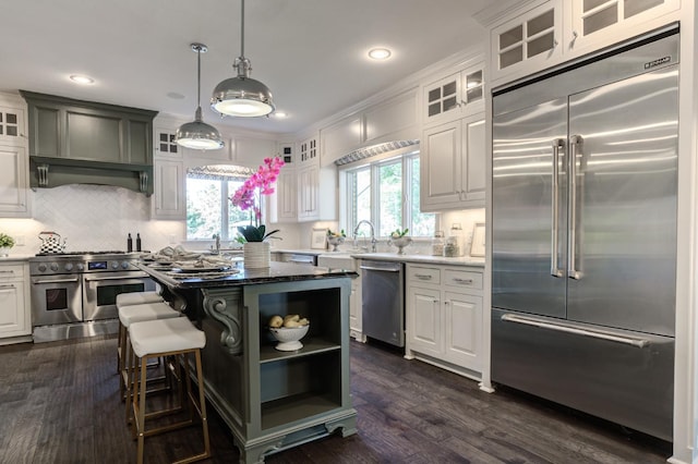 kitchen with dark wood-type flooring, white cabinetry, a kitchen breakfast bar, high end appliances, and a kitchen island