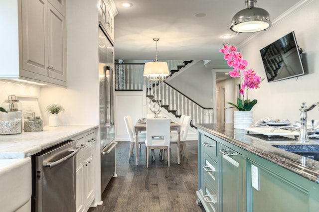 kitchen with crown molding, appliances with stainless steel finishes, hanging light fixtures, green cabinetry, and dark hardwood / wood-style flooring