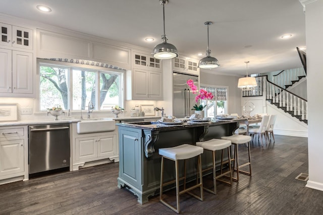 kitchen with white cabinetry, appliances with stainless steel finishes, sink, and a kitchen island