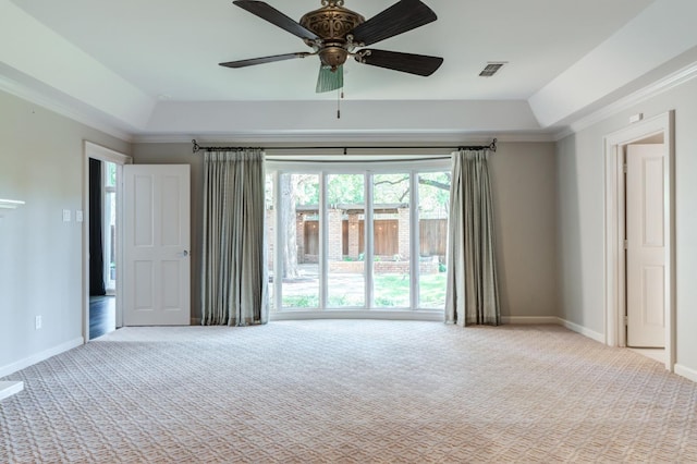 unfurnished room with crown molding, light colored carpet, and a raised ceiling