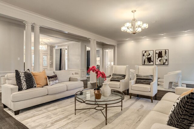 living room with a notable chandelier, crown molding, light wood-type flooring, and ornate columns