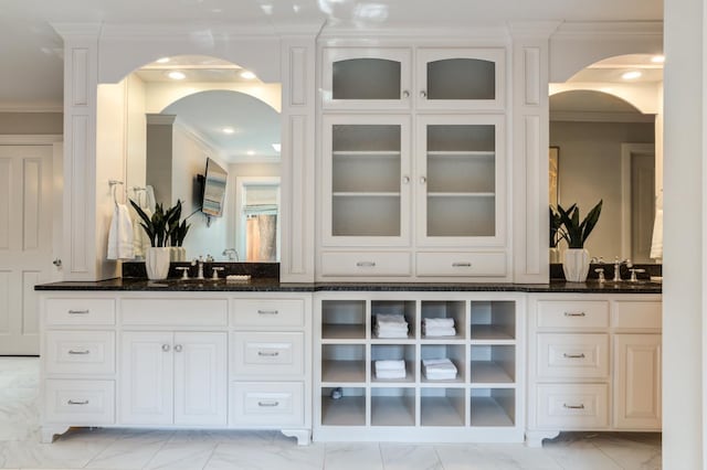 bar with white cabinets, ornamental molding, and dark stone counters