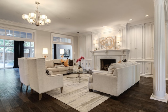 living room featuring a notable chandelier, ornamental molding, dark hardwood / wood-style floors, and ornate columns