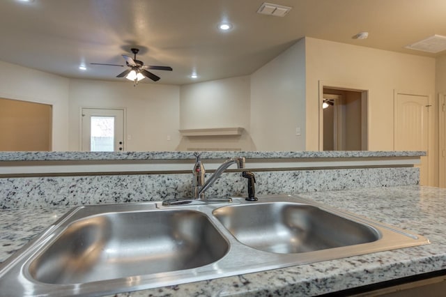 room details featuring light stone counters, sink, and ceiling fan