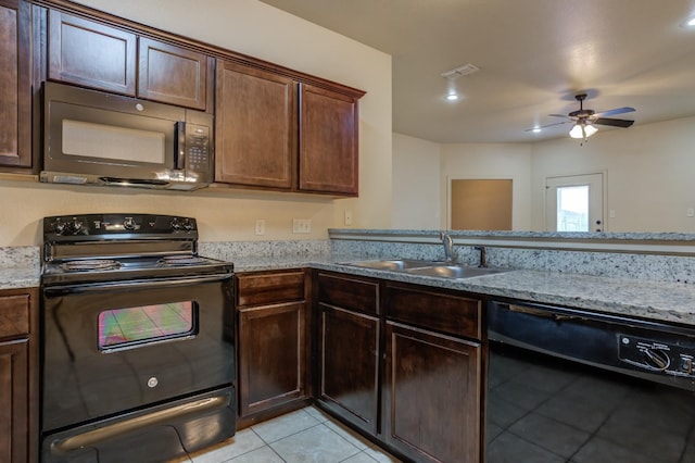 kitchen featuring black appliances, dark brown cabinetry, light tile patterned floors, light stone countertops, and sink