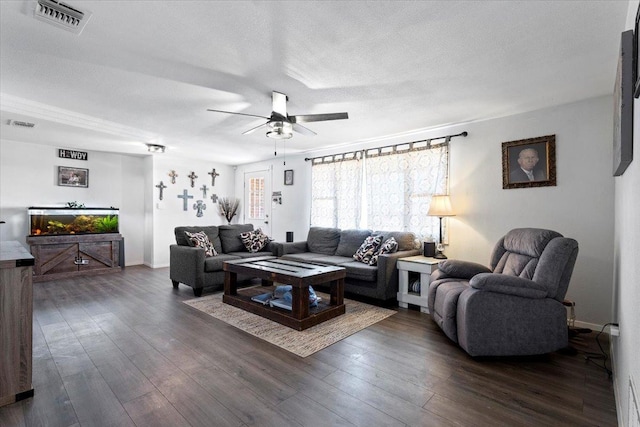 living room featuring ceiling fan, dark wood-type flooring, and a textured ceiling