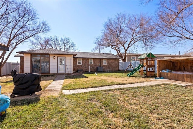 back of house featuring an outbuilding, a lawn, a playground, and central air condition unit