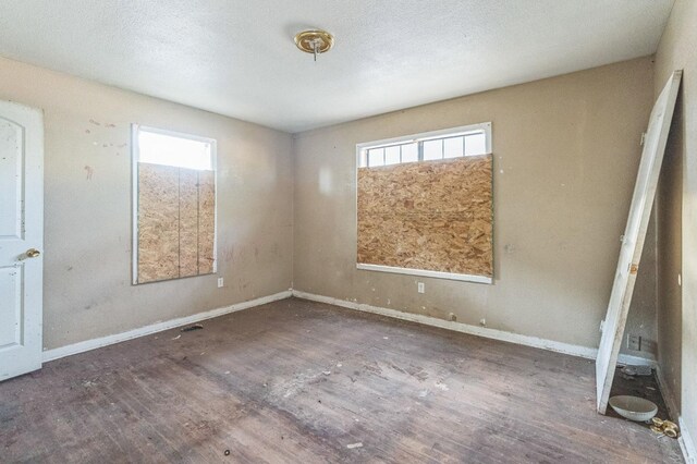 empty room with dark wood-type flooring and a wealth of natural light