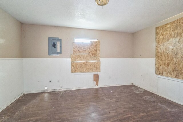 empty room with dark hardwood / wood-style flooring and electric panel