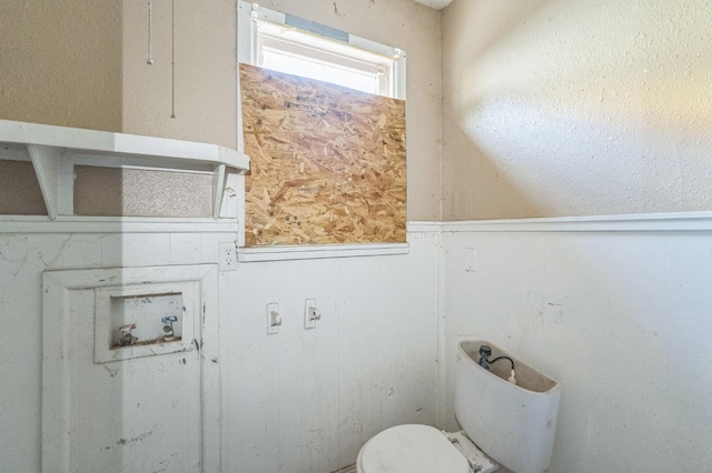 bathroom featuring wooden walls and toilet