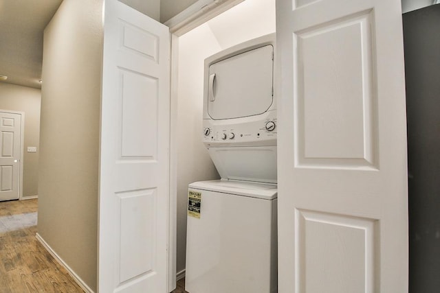 washroom with stacked washing maching and dryer and light hardwood / wood-style flooring