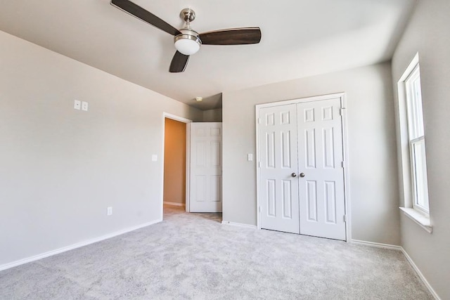 unfurnished bedroom featuring ceiling fan, light colored carpet, and a closet