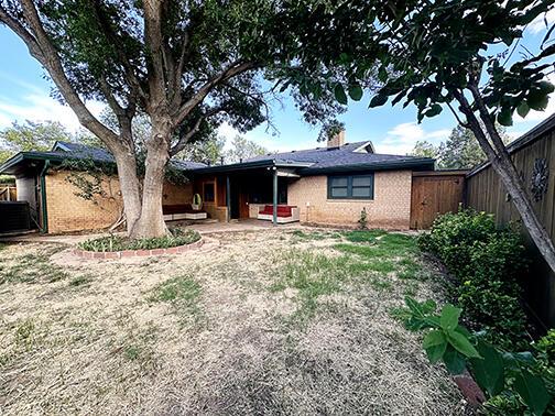 5712 70th Pl, Lubbock, TX 79424 - rear view of property with a chimney and brick siding