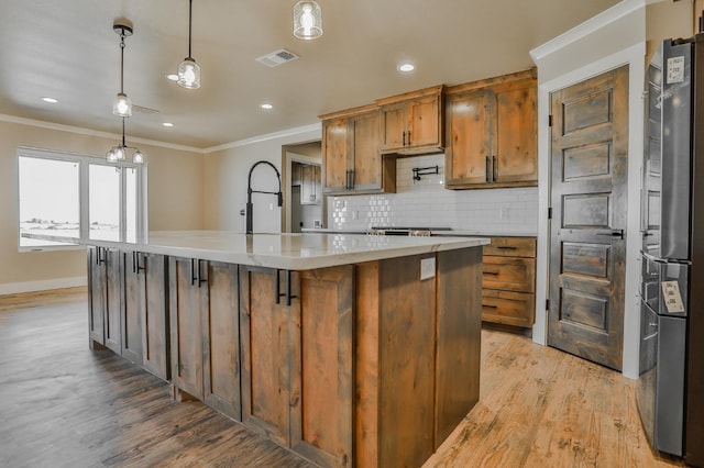 kitchen with sink, crown molding, hanging light fixtures, light hardwood / wood-style floors, and a kitchen island