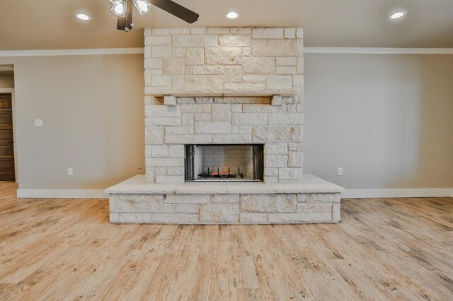 unfurnished living room with ornamental molding, a stone fireplace, hardwood / wood-style floors, and ceiling fan