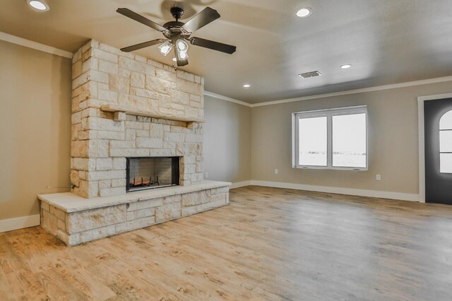 unfurnished living room with crown molding, a stone fireplace, and light hardwood / wood-style flooring