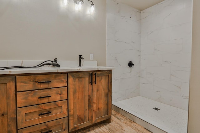 bathroom with hardwood / wood-style floors, vanity, and a tile shower