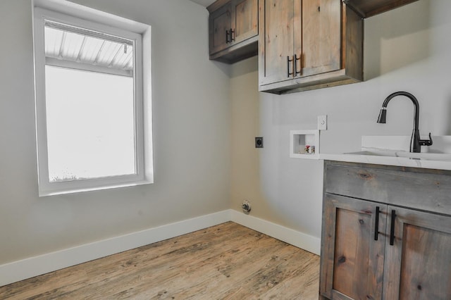 laundry room featuring sink, cabinets, hookup for a washing machine, hookup for an electric dryer, and light hardwood / wood-style floors