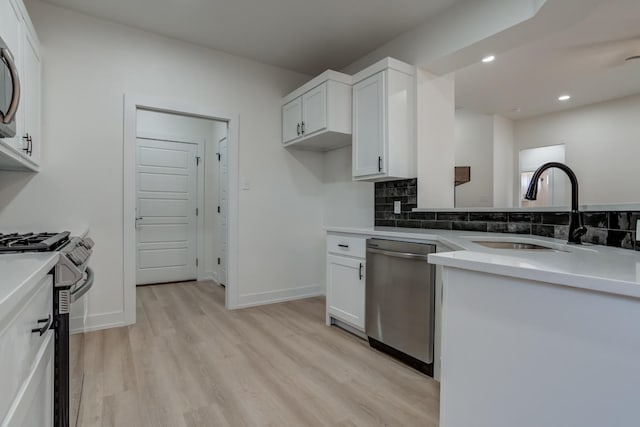 kitchen featuring sink, white cabinetry, stainless steel appliances, decorative backsplash, and light wood-type flooring