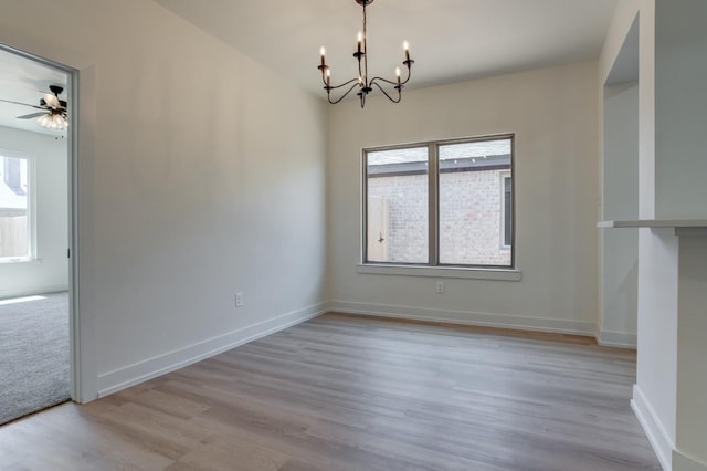 empty room featuring ceiling fan with notable chandelier and light hardwood / wood-style flooring