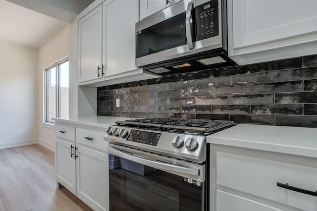 kitchen with stainless steel appliances, white cabinetry, light hardwood / wood-style floors, and decorative backsplash