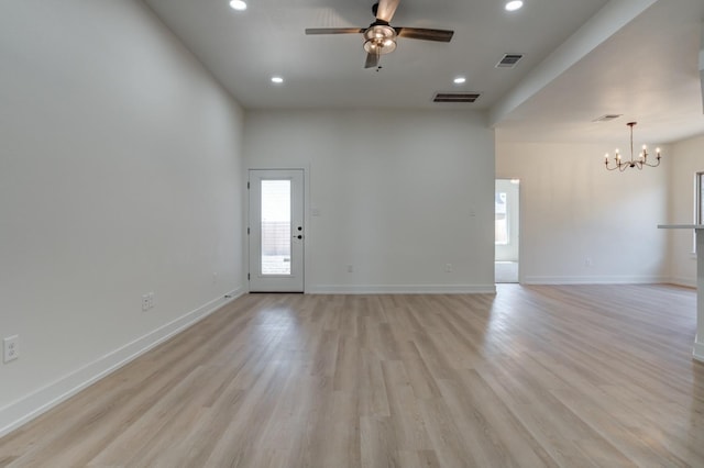 empty room with ceiling fan with notable chandelier and light hardwood / wood-style floors