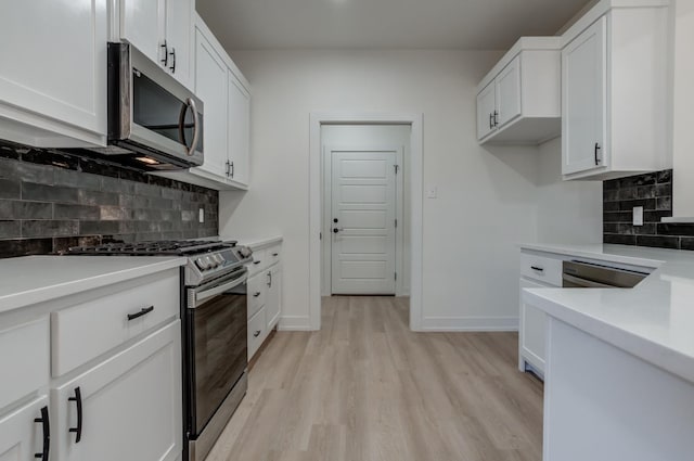 kitchen featuring decorative backsplash, light hardwood / wood-style floors, white cabinets, and appliances with stainless steel finishes