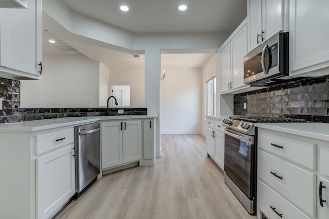 kitchen featuring sink, stainless steel appliances, light hardwood / wood-style floors, white cabinets, and decorative backsplash