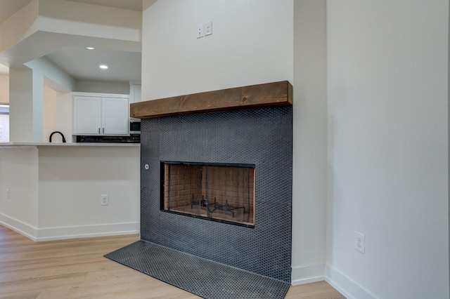 interior details with a tiled fireplace, hardwood / wood-style floors, and sink