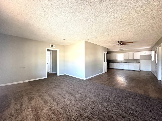 unfurnished living room featuring dark colored carpet, a textured ceiling, and ceiling fan