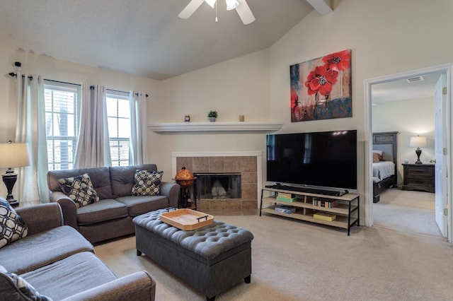 living room featuring ceiling fan, a tile fireplace, lofted ceiling with beams, and carpet