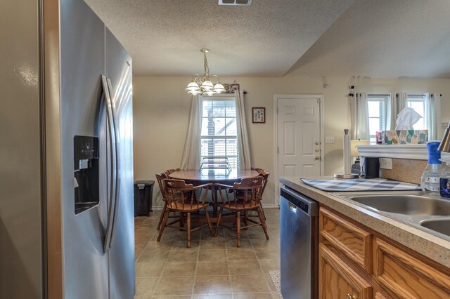 kitchen featuring pendant lighting, a notable chandelier, a wealth of natural light, and appliances with stainless steel finishes