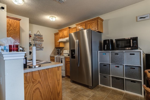 kitchen with stainless steel appliances, dark tile patterned flooring, and a textured ceiling