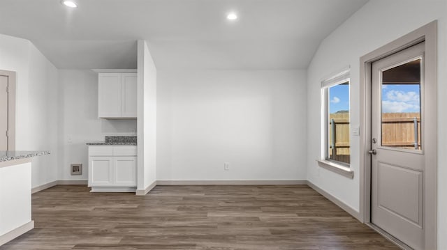 unfurnished dining area featuring vaulted ceiling and dark hardwood / wood-style flooring