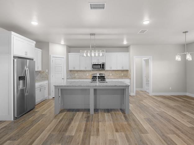 kitchen featuring stainless steel appliances, white cabinetry, and tasteful backsplash