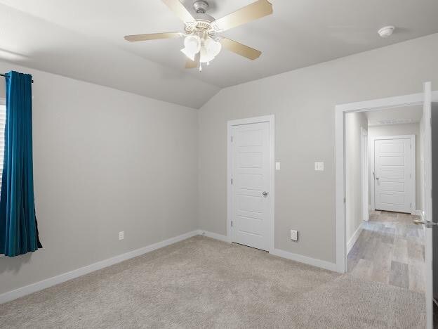 unfurnished bedroom with lofted ceiling, light colored carpet, and ceiling fan